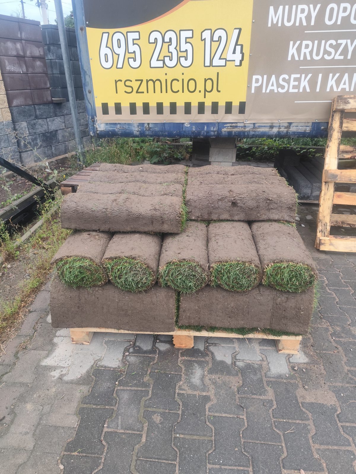 Rolki trawy ułożone warstwami na drewnianej palecie